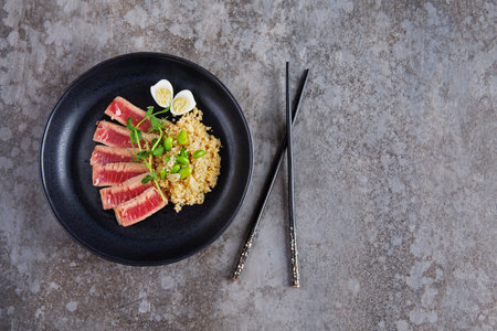 Fried pieces of tuna with kenoa and beans in a plate on a gray background. Flat layの写真素材