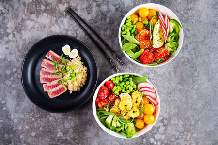 Two plates with poke and a plate with fried tuna on a gray background. Flat layの写真素材