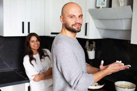 Young man and woman preparing pancakes in their kitchen at homeの写真素材