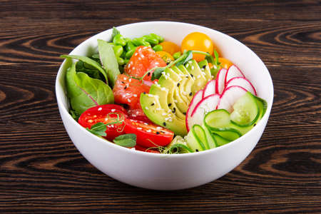 Plate with salmon, tomato, avocado and quinoa poke on the tableの写真素材