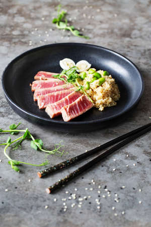 Plate with quinoa and slices of fried tuna on gray backgroundの写真素材