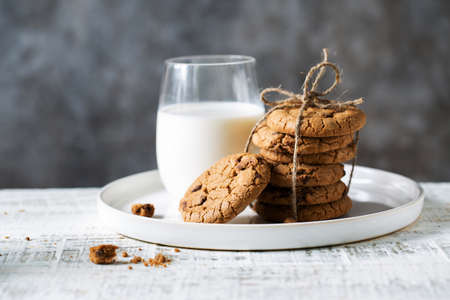 Oatmeal cookies and a glass of milk in a white plate on the tableの写真素材