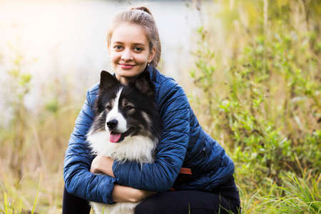 Cute girl sits next to her beloved dog and hugs herの写真素材
