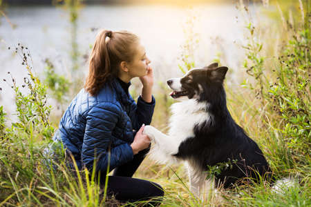 Cute girl sits next to her beloved dog and trains herの写真素材