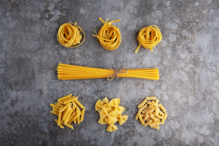Five types of different pasta lie on a gray table. Flat layの写真素材