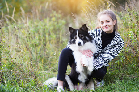 Attractive girl sitting next to her dog in the grassの写真素材