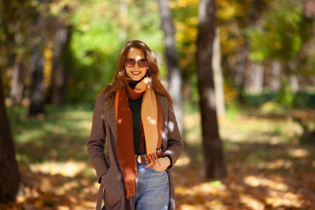 Beautiful young woman in sunglasses walks in the autumn forestの写真素材