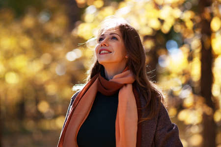 Beautiful young woman in autumn park on a sunny dayの写真素材