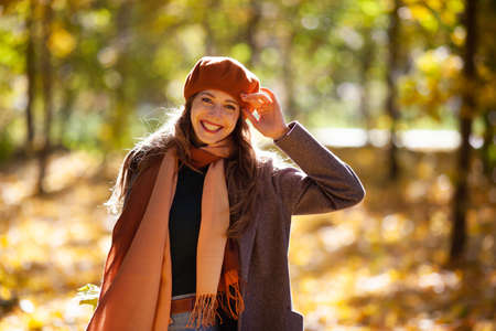 Happy smiling woman in orange beret in autumn sunny forestの写真素材