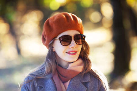 Young woman in orange beret and sunglasses in autumn parkの写真素材