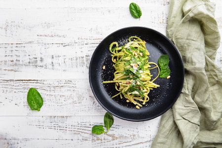 Italian spaghetti with spinach, pine nuts and parmesan on a light gray table. Flat layの写真素材