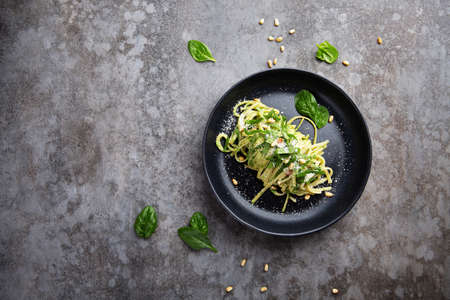 Spaghetti with spinach, pine nuts and parmesan cheese on a plate on a gray table. Flat layの写真素材