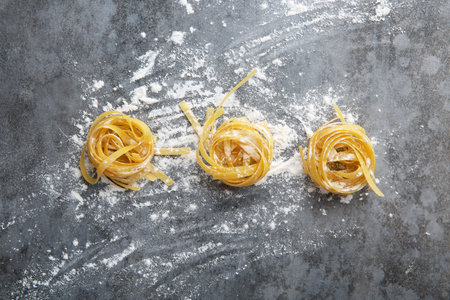 Three balls of rolled spaghetti in flour on gray backgroundの写真素材