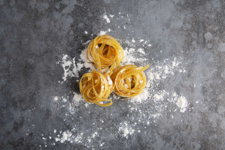 Three balls of rolled spaghetti in flour lie on a gray tableの写真素材