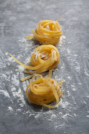 Three balls of rolled spaghetti in flour lie on a gray backgroundの写真素材