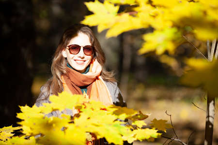 Beautiful young woman in sunglasses among autumn maple leavesの写真素材