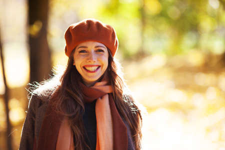 Young happy woman in beret in autumn park on a sunny dayの写真素材