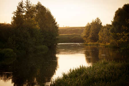 Beautiful summer landscape with a flowing river in the evening at sunsetの写真素材