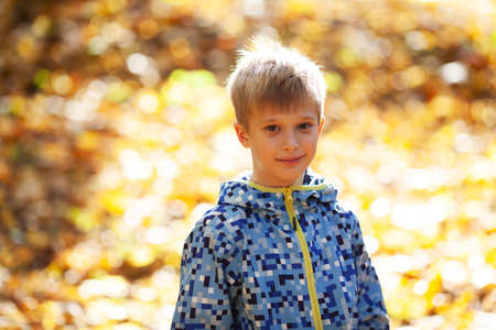 Portrait of a happy smiling blonde boy in the rays of the autumn sunの写真素材