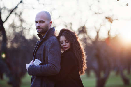 Happy lovers stand in the autumn garden in the rays of the setting sunの写真素材