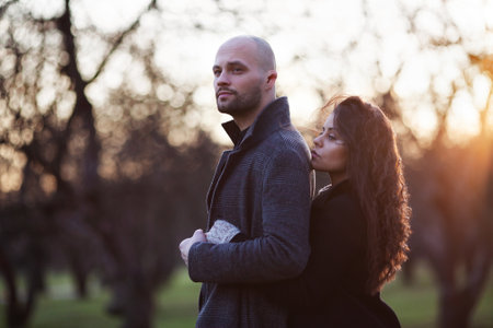Happy couple: man and woman stand in the autumn garden in the rays of the evening sunの写真素材