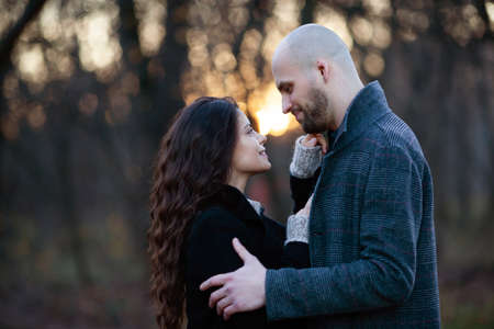 Young man and woman stand and hug in the park in the eveningの写真素材