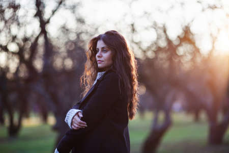 Young beautiful woman stands in the autumn park in the eveningの写真素材
