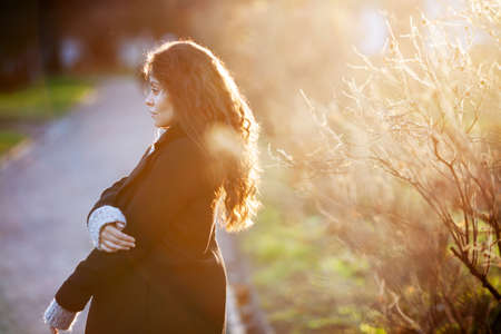 Pretty young woman in a coat in the rays of the autumn evening sunの写真素材