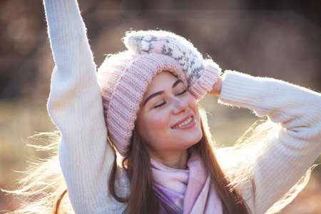 Portrait of a beautiful happy young woman in a knitted hat and mittensの写真素材