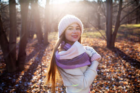 Happy beautiful young woman walking in the autumn park on a sunny dayの写真素材