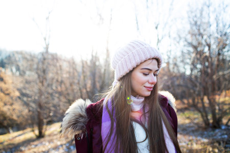 Beautiful young woman in a knitted hat walks in the autumn parkの写真素材
