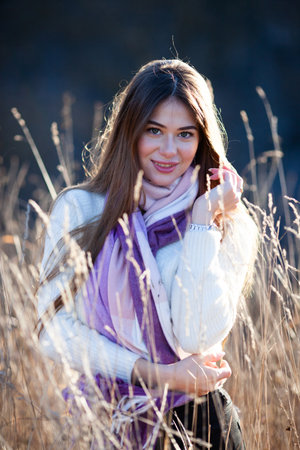 Portrait of a beautiful young woman who stands in tall autumn grassの写真素材
