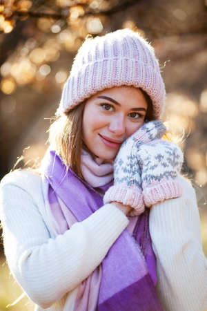 Portrait of a beautiful young woman in a knitted hat and mittensの写真素材