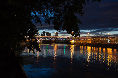 Night view of the river and the bridge over it. A small boat floats on the river.の写真素材