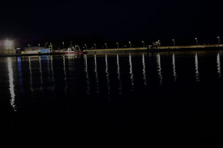 The photo shows a night view of the port in Hel city. The lights reflect on the water, creating a calm and peaceful atmosphereの写真素材