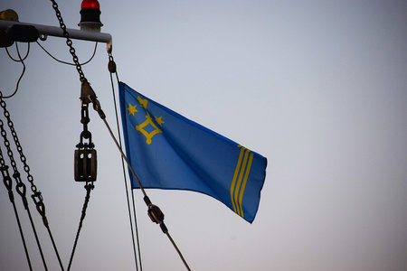 The photo shows a flag waving on a ship mast. The flag details and maritime environment create a vibrant atmosphereの写真素材