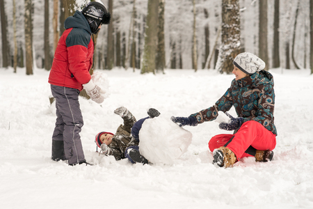 Mother and two sons play  molded from snow snowmen in the winの写真素材