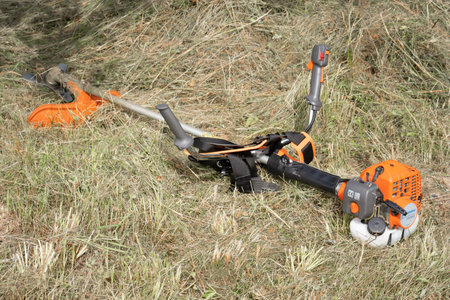 Minsk, Belarus - 02/08/2020 Petrol scythe trimmer brushcutter Husqvarna 143R-II lies on the mown hay...