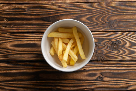 A small portion of French fries in a deep white ceramic bowl.