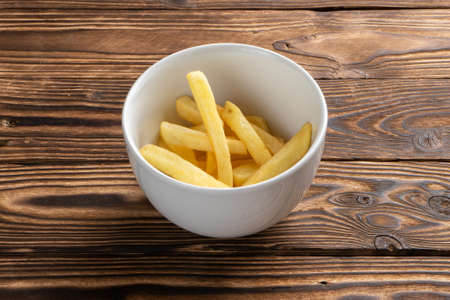 A small portion of French fries in a deep white ceramic bowl.の写真素材