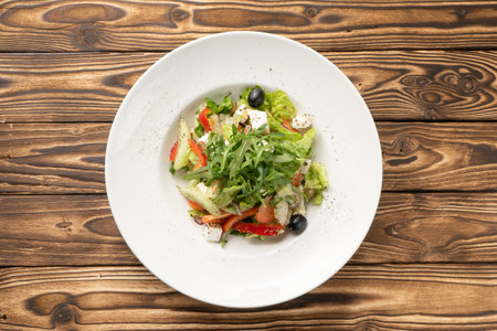 Vegetarian Greek vegetable salad with arugula, olives and feta cheese in a white ceramic plateの写真素材