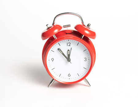 Classic red mechanical alarm clock in retro style on a white backgroundの写真素材