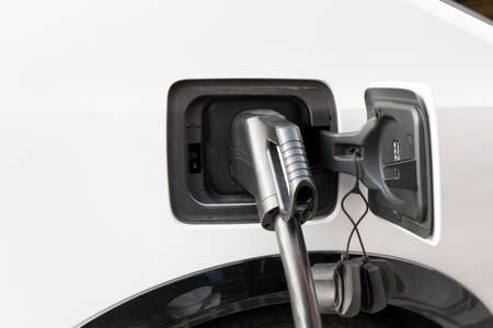 A modern electric car connected to a power supply unit charges the batteries at a fast charging stationの写真素材