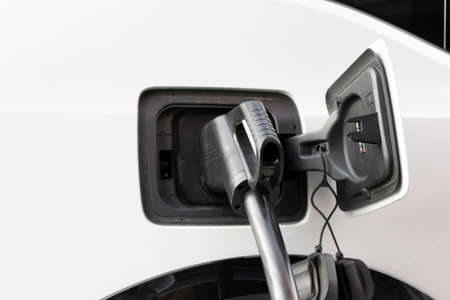A modern electric car connected to a power supply unit charges the batteries at a fast charging stationの写真素材