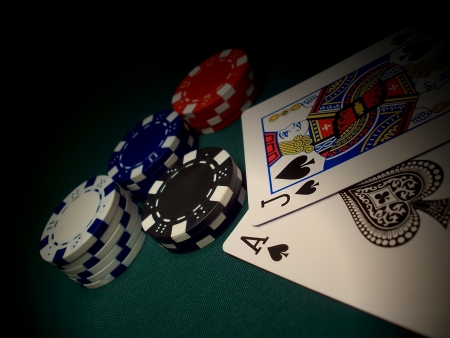 Red, blue, white, black poker chips on a green felt gaming table. Two cards and chips are spotlighted.  Jack of Spades and Ace of Spades gives a Blackjack winner.のeditorial素材