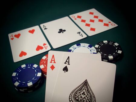 Three cards face up and multi-colored poker chips on a green felt table. This is known as The Flop in the popular poker game Texas Hold 'Em. The player is holding two Aces and another one on the table, a very good hand. Bet high!のeditorial素材