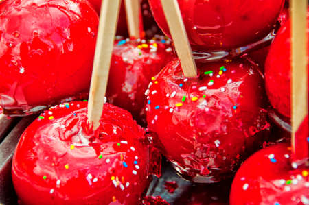 Toffee apples in sugar icing on sticks with tiny colorful candiesの写真素材
