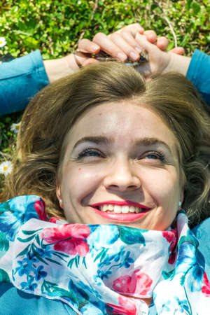 Young woman with scarf lying on the grass in parkの写真素材
