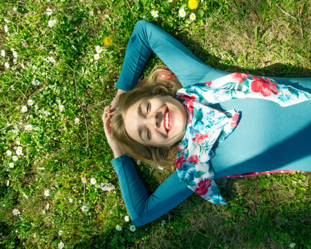 Young smiling woman lying on the graas in park