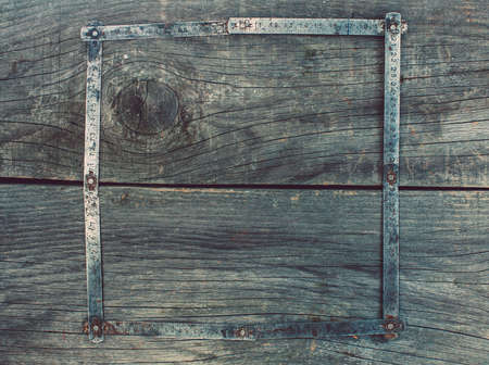 On the old, wooden, cracked, the working surface in the workshop is a vintage, used, rusty, darkened, foldable measuring tool - meter curved in the shape of a square frame form.の写真素材